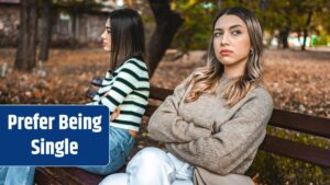 Two women sit apart on a park bench angry at each other.